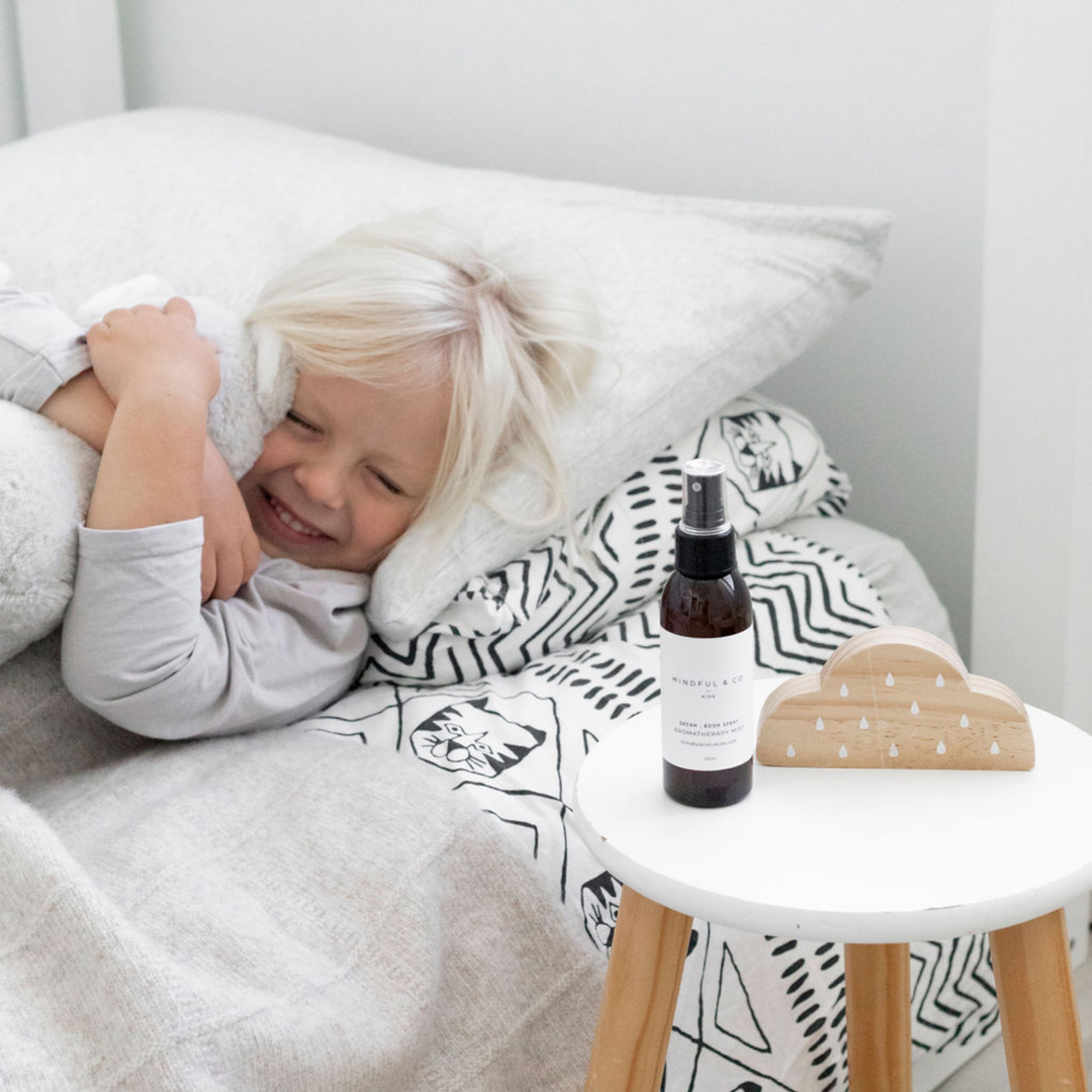 Child in bed with spray bottle and cloud decor.